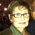 Headshot of Audrey McLaughin wearing a green coat and glasses.