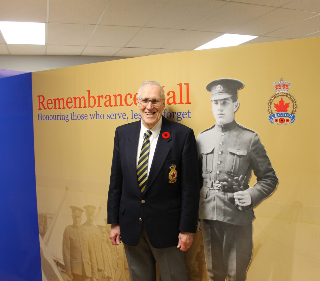 Man standing in front of Remembrance Hall sign