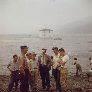 Men standing on shore of output [sic, outport], 1961. Source: Library and Archives Canada/National Film Board fonds/e010975945.