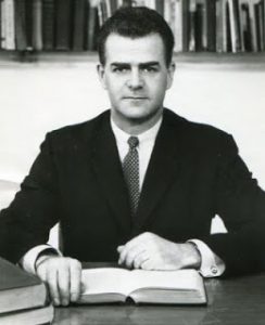 Frank Howard in a suit sitting at a desk