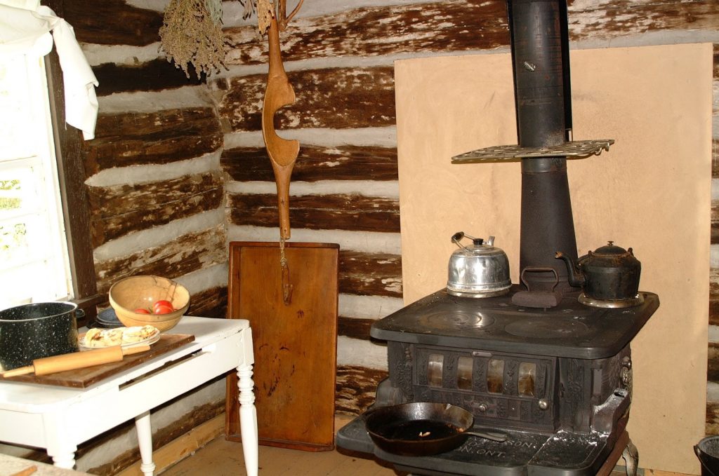 Stove, side table, and pots in a pioneer cabin.