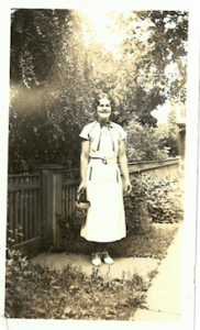 Photograph of a woman wearing a dress standing in a garden