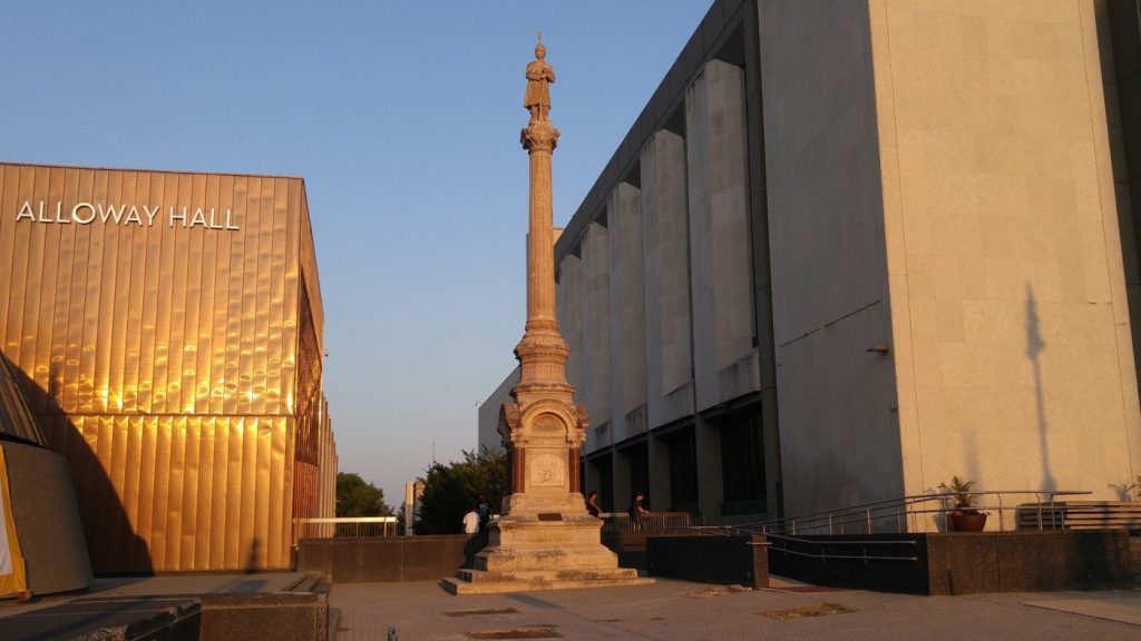 An image of a tall stone monument that features a lone soldier standing on top of a fluted classical column.