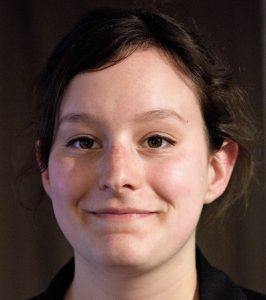 Close-up photo of a white femme with brown hair and brown eyes.