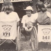 Two people in wheelchairs speaking to someone crouched in front of them
