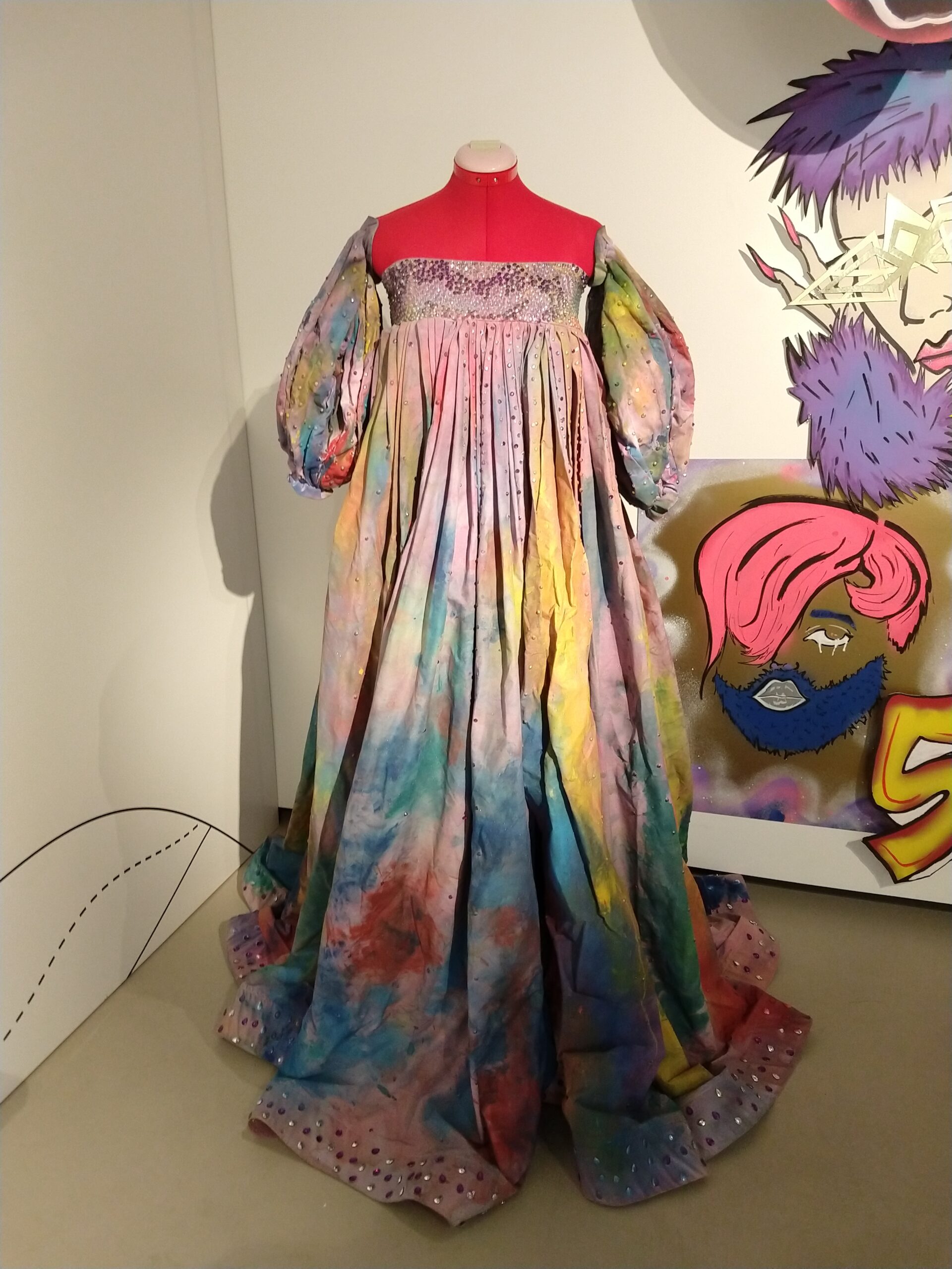 A multicoloured dress on a hot pink mannequin.