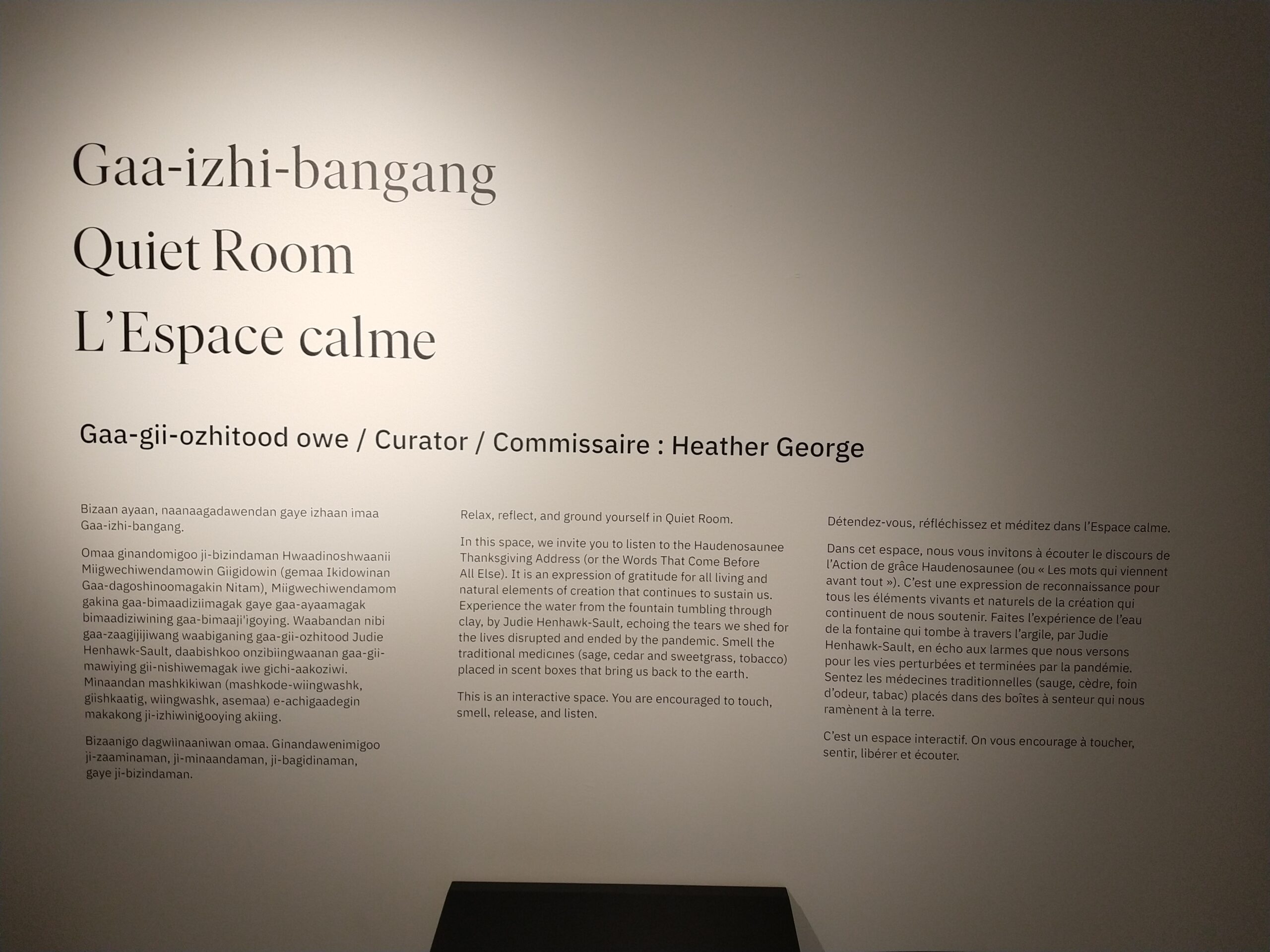 A white wall with black text in Anishinaabemowin, English, and French.