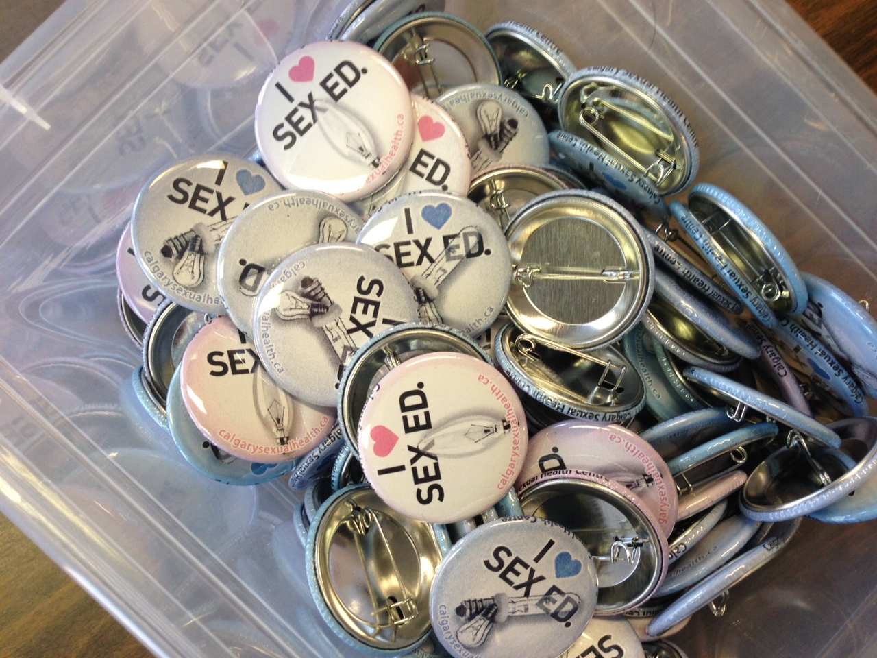 Photograph of a pile of buttons that read I [Heart] Sex Ed.