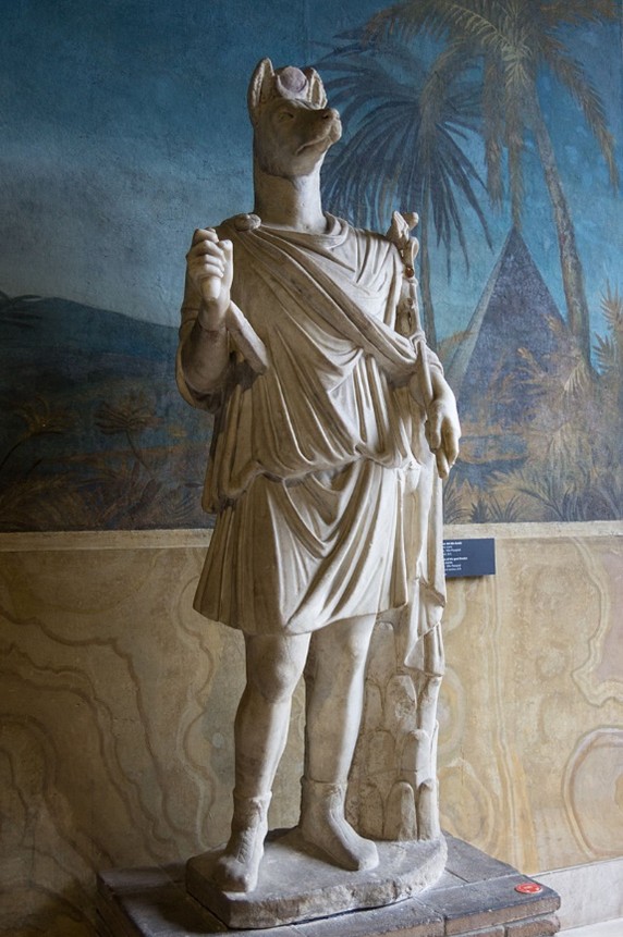 Marble statue of a being with a human body and a wolf's head.