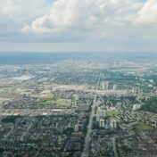 Colour photograph of a city landscape from high above. A lake is visible on the horizon.