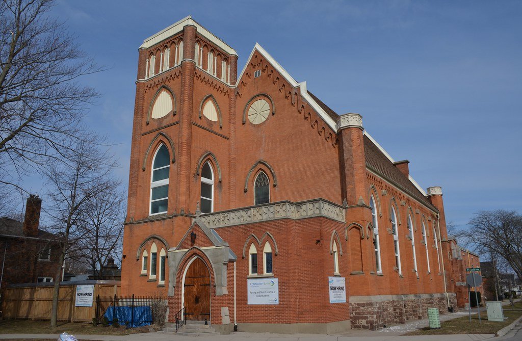 Colour photograph of a large red-brick church with a blue sky in the background.