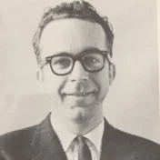 Head shot of Robert Carney wearing a suit and glasses.