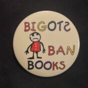 Photograph of a button reading "Bigots Ban Books" in rainbow text.