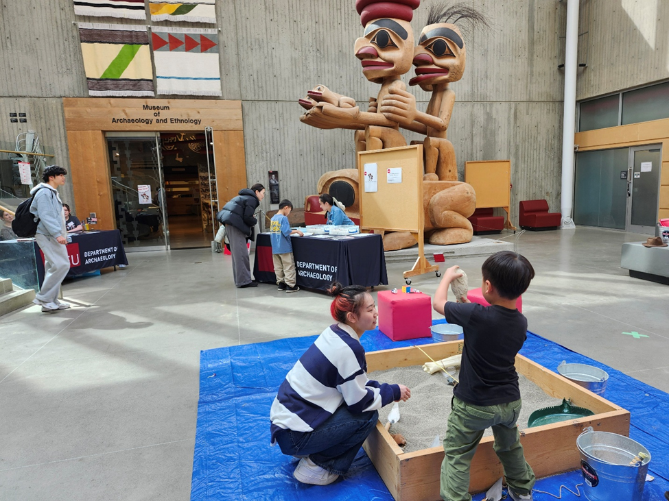 Students and families enjoy International Museum Day Event. They are handling artifacts and learning about history through activities. 