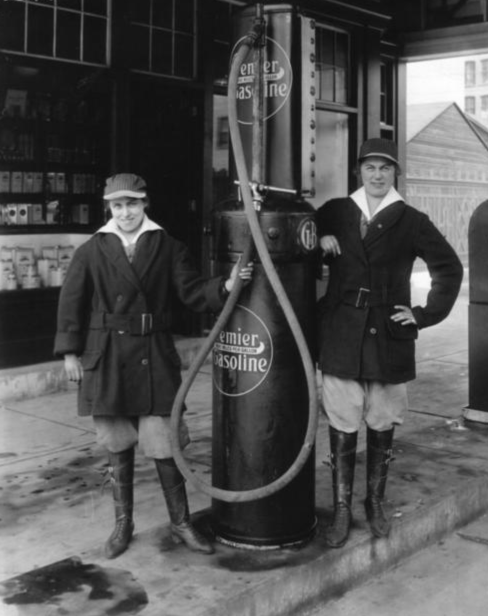 Two women strikebreakers working at a gas station, posing beside a gas pump.