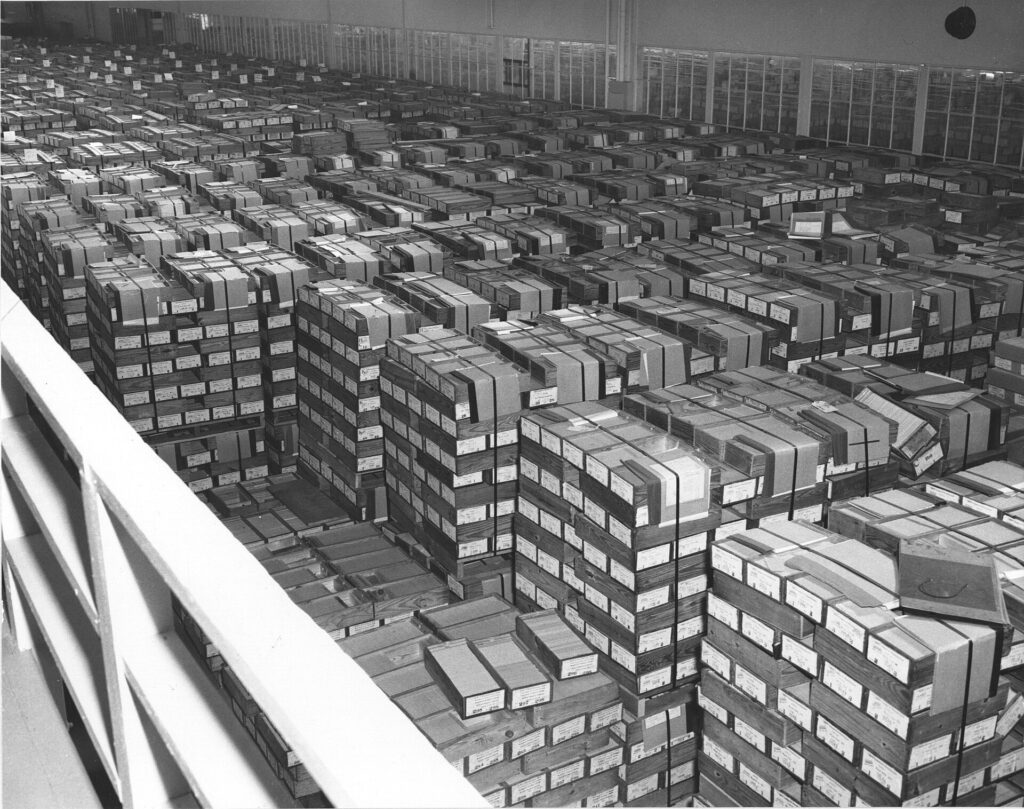 Black and white photo of hundreds of stacked, labeled boxes, viewed from above.