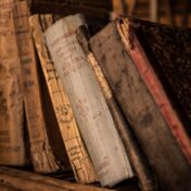 Colour photograph of old hardback books on a shelf.